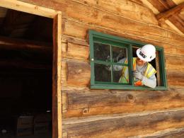 Preservation Maintenance Worker works on a restored window on the historic Wade and Curtis cabin at Gates of Lodore in Dinosaur National Monument