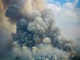 A tall plume of smoke rises from a wildfire burning through a forest in Alaska. Photo by BLM.
