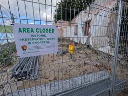 Image of the ruins at Cinnamon Bay surrounded by a fence with a sign that reads, Area Closed, Historic Preservation Work in Progress.