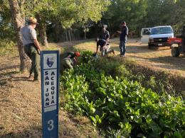 Staff work together around a historic irrigation ditch with San Juan Acequia sign in the foreground. 