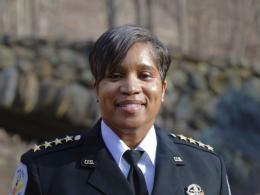 Pamela A. Smith, Chief of the U.S. Park Police, stand in front of a stone bridge in Rock Creek Park.