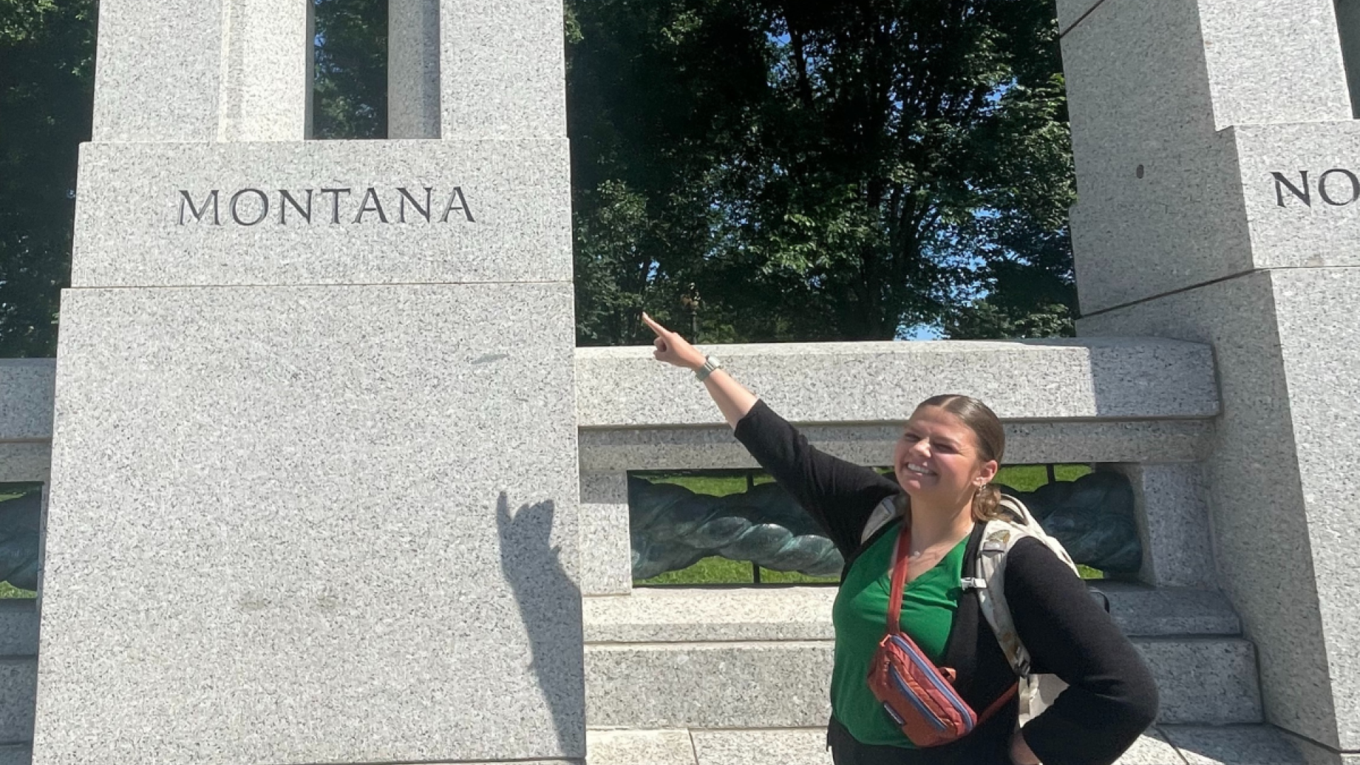 Zoe Belinda, Office of Wildland Fire intern, standing next to the Montana block of the World War II Memorial in Washington D.C. She points to the word "Montana."
