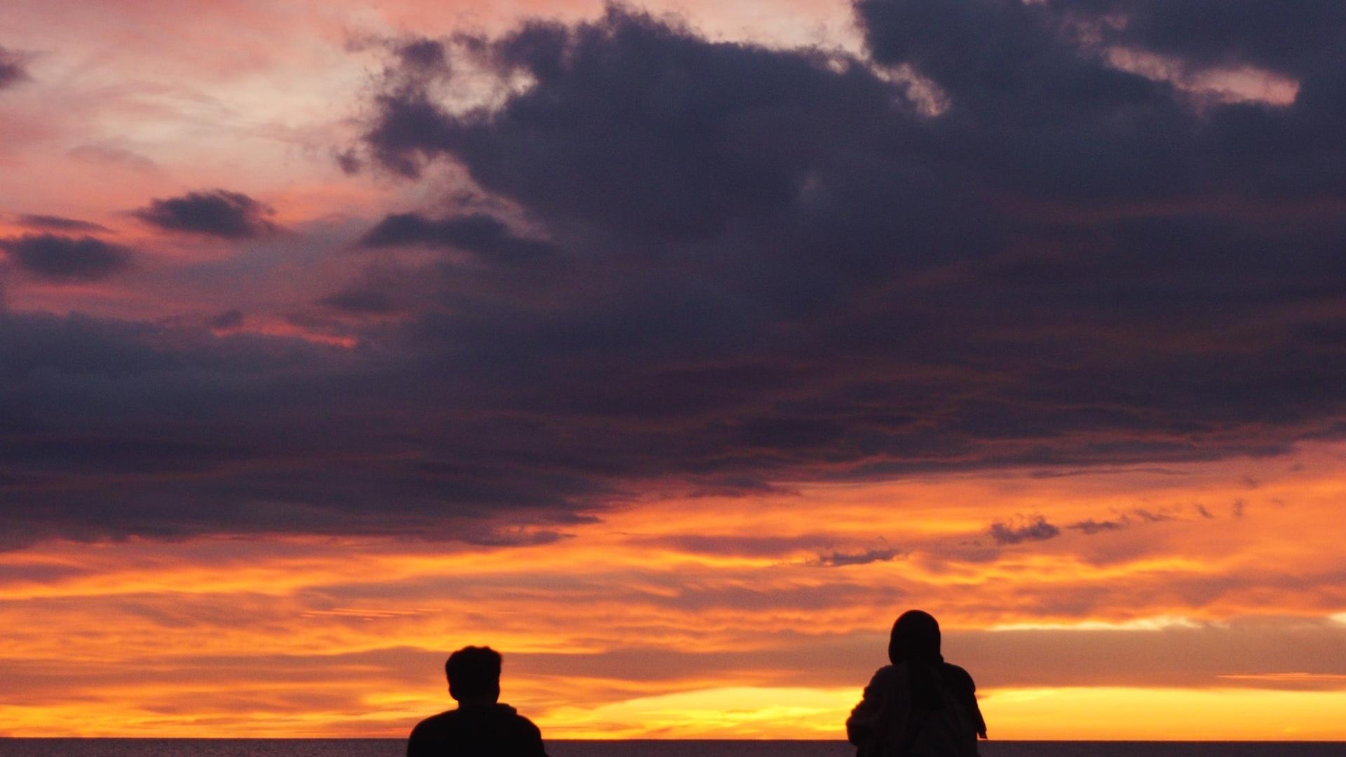 Picture of Couple Sitting on Beach at Sunset