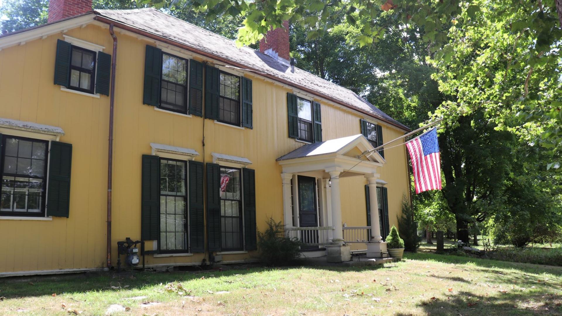 Large yellow two story house with American flag on porch