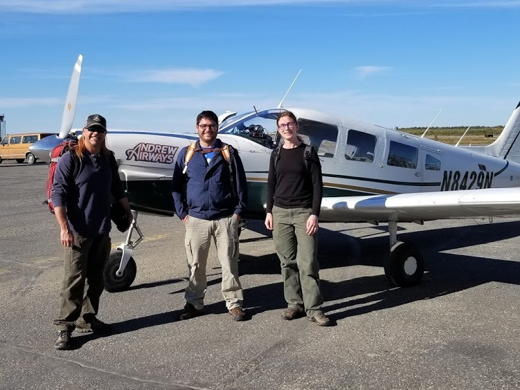 Three people standing in front of a small plane