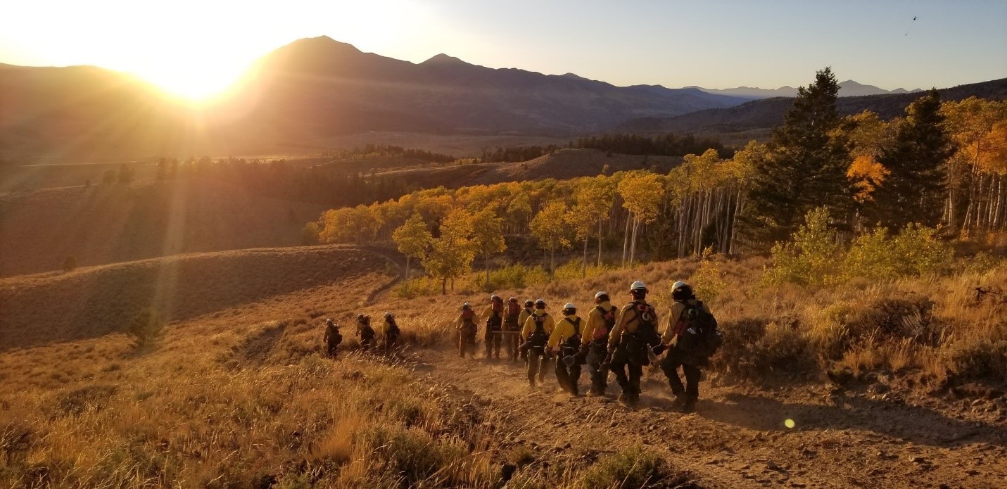 Hand crew walks toward the mountains at sunset.