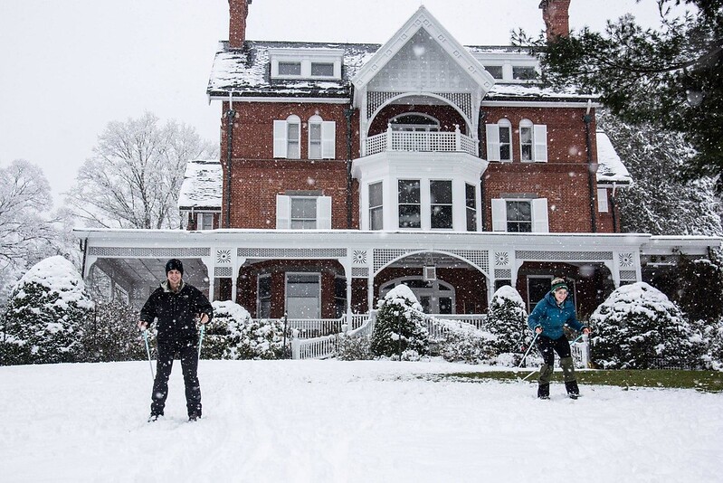 Skiiers in front of the The Marsh-Billings-Rockefeller Mansion, a large brick building.
