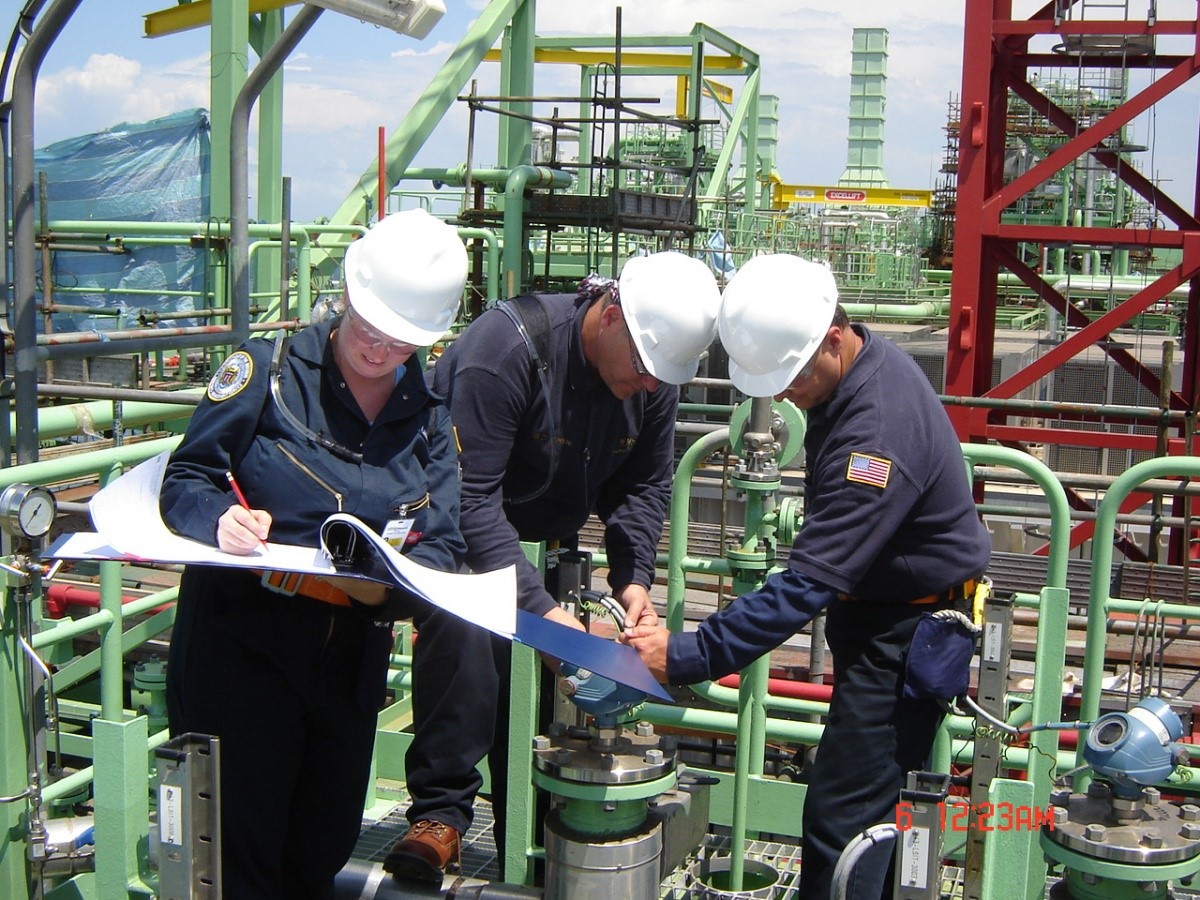 A group of engineers reviews materials on an oil rig.