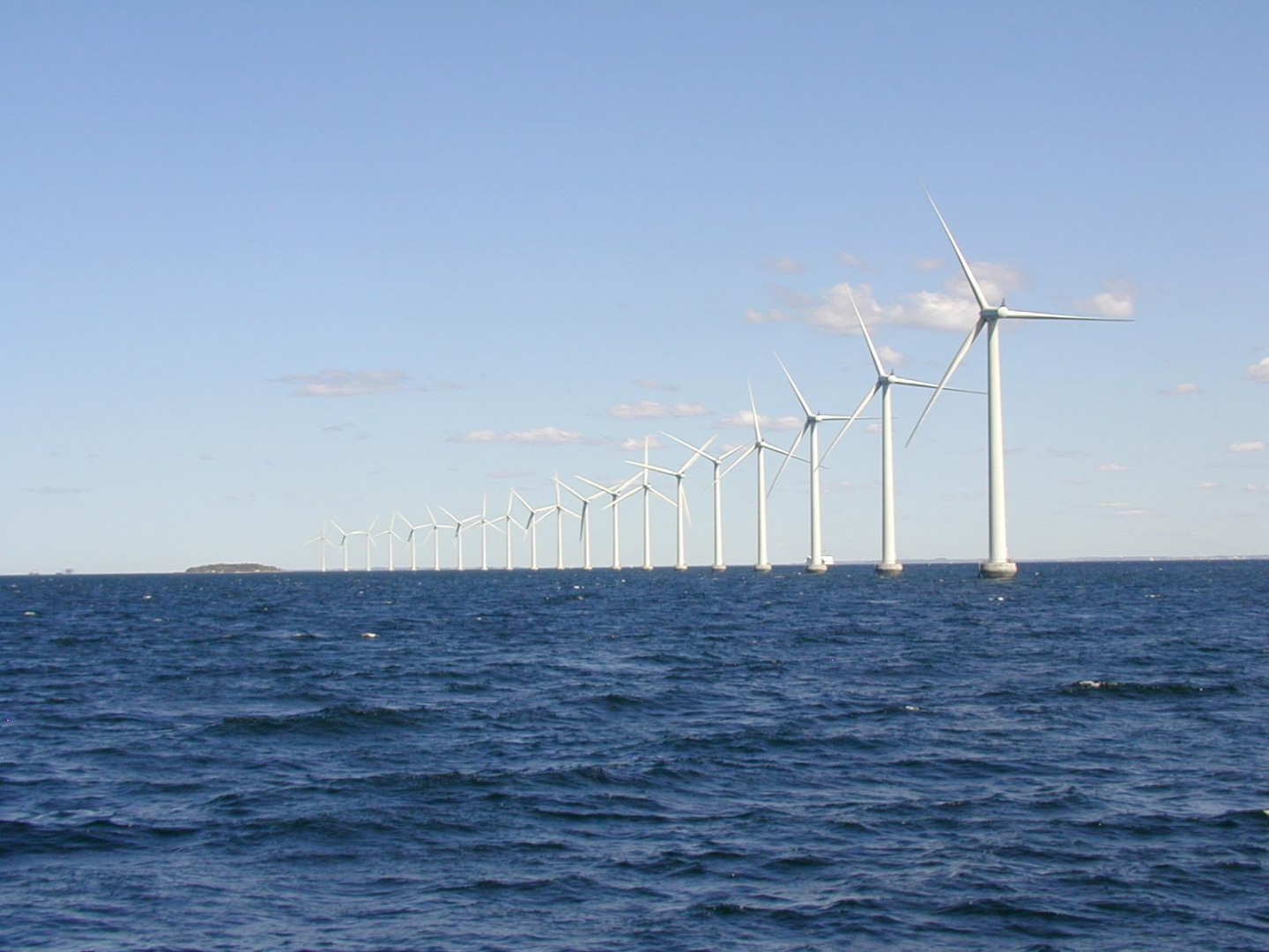 Offshore windfarm featuring a line of turbines in the ocean.