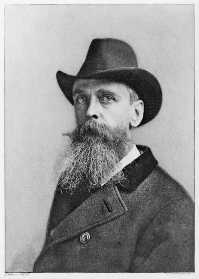 Historic black and white photo of a white man with a long beard wearing a top hat.