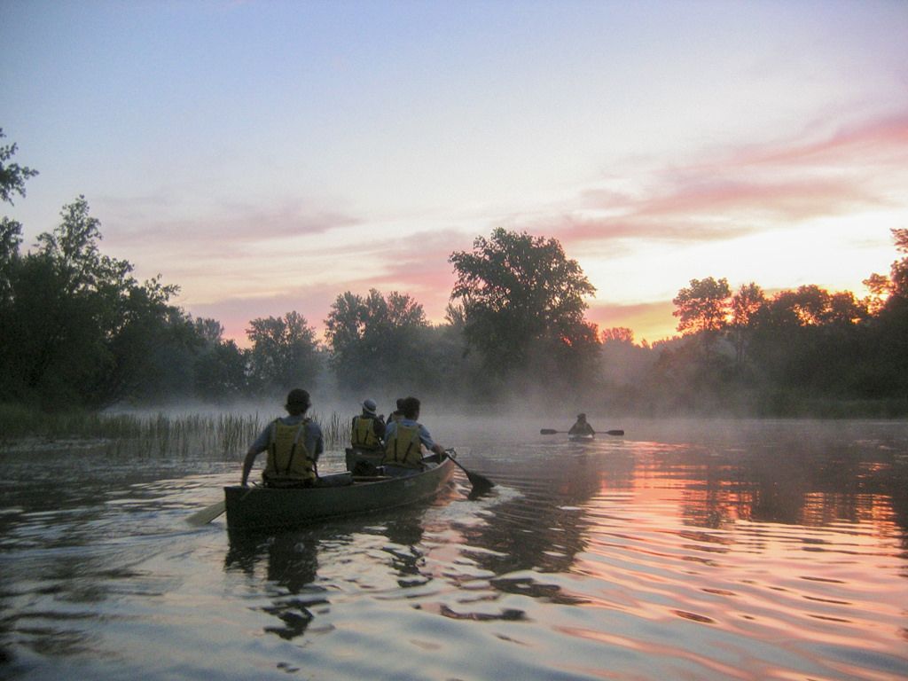 Two canoes paddle through the St. Croix Wild and Scenic River at sunset.