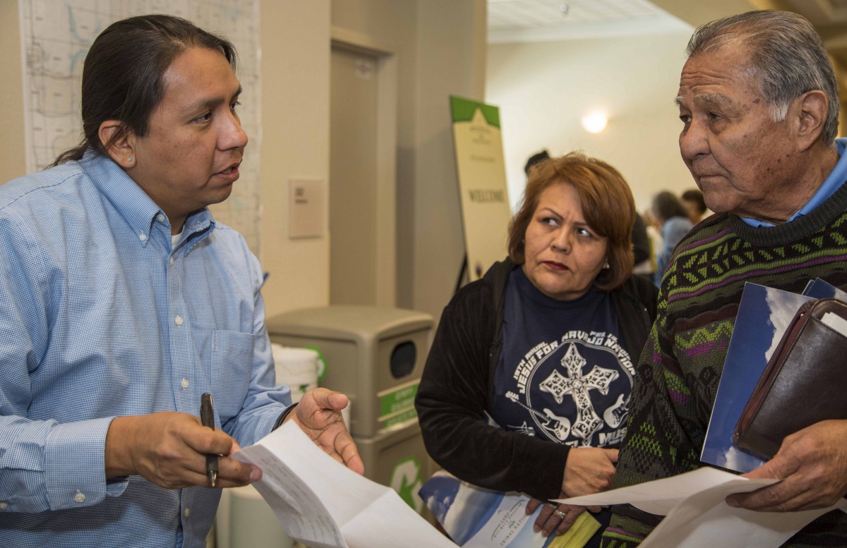 An Interior employee talks to an older Native American man and woman inside a room.