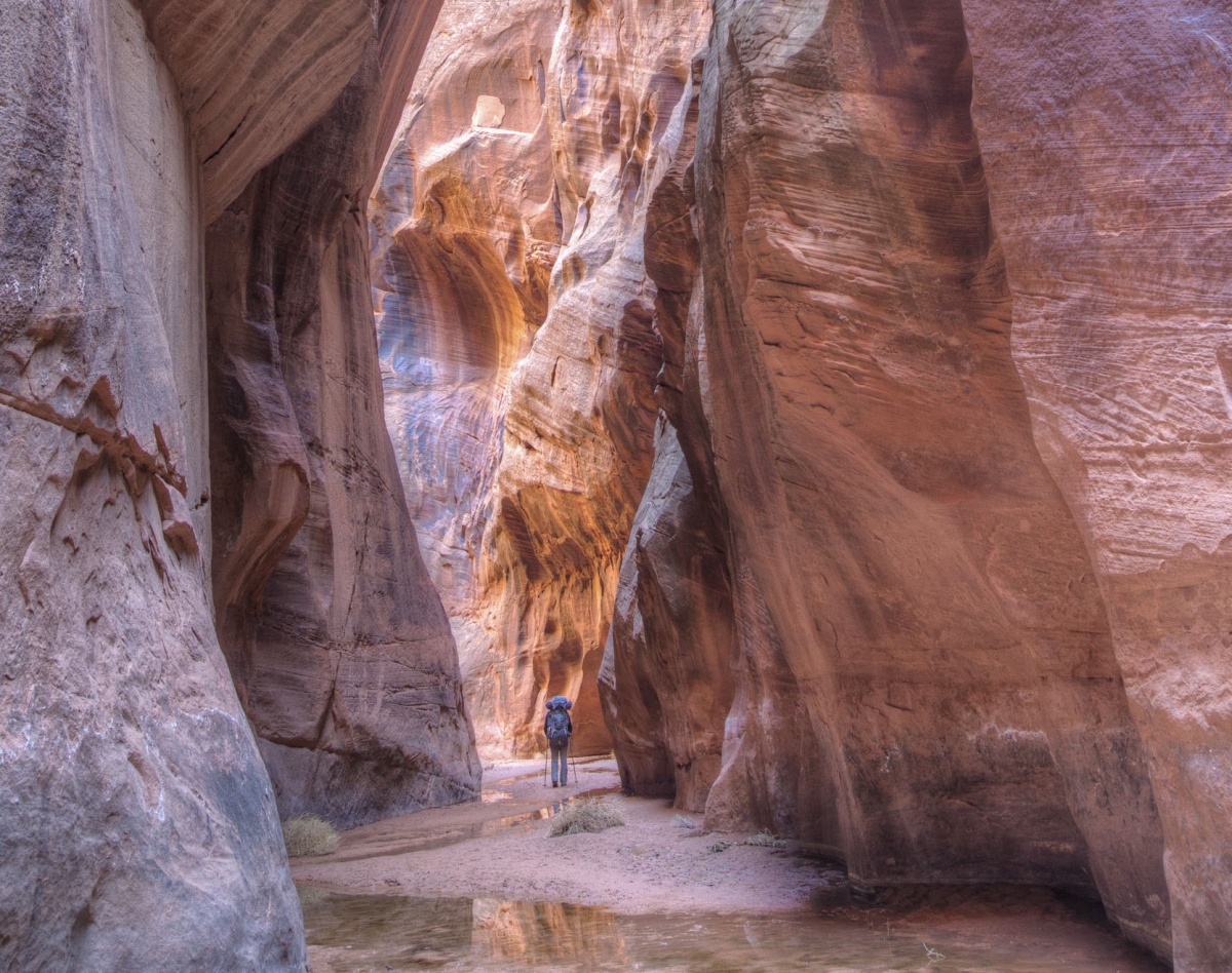 a hiker walks through tall canyon walls