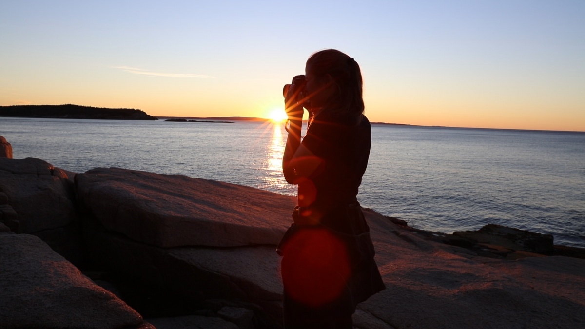 A woman's silhouette against a sun setting over the water. 