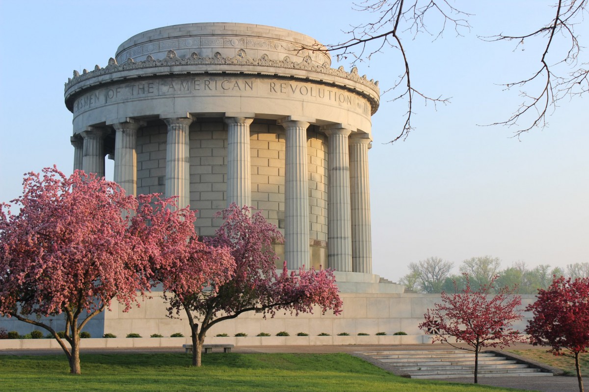Cherry blossoms bloom in front of white memorial.