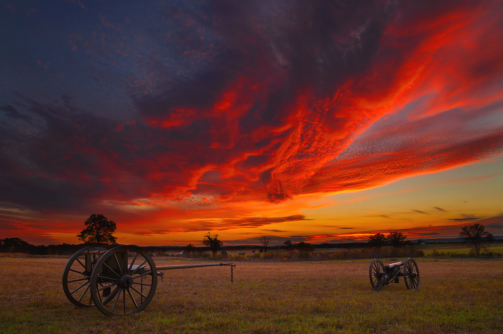 red skies over a grassy meadow with two cannons