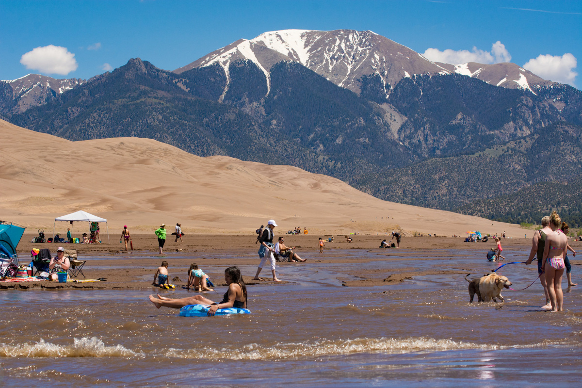 Visitors ride rafts, sit in chairs, and walk dogs in the shallow creek.