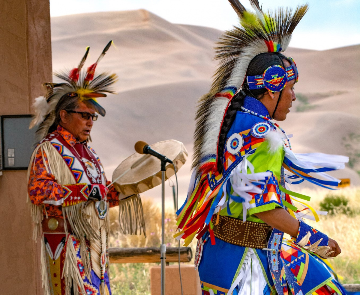 Two members of the Jicarilla Apache tribe play instruments on a stage at the park. 