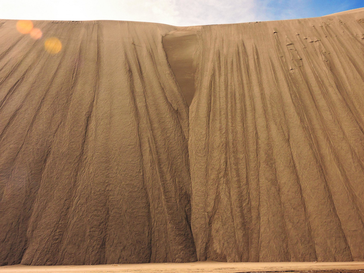 A steep avalanche occurs on the face of a dune. Ripples in the dune indicate the sand is sliding down quickly.