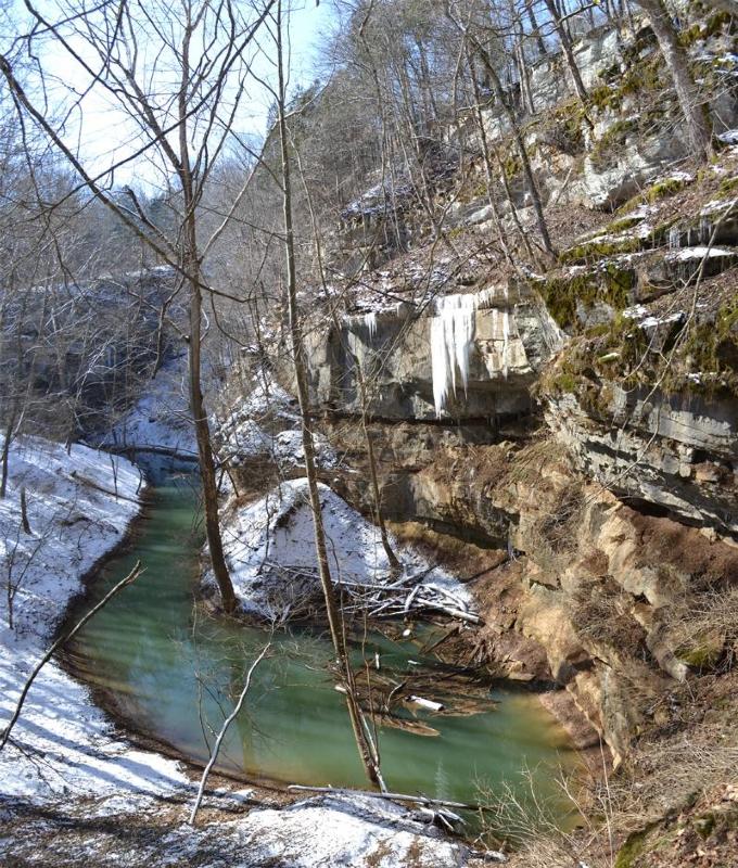A stream runs through snow covered hills outside of Mammoth Cave.