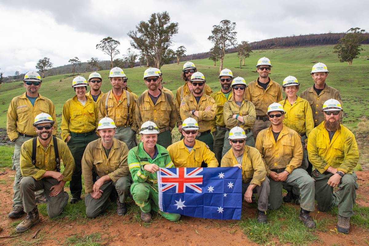 A group of American and Australian firefighters holding an Australian Flag.