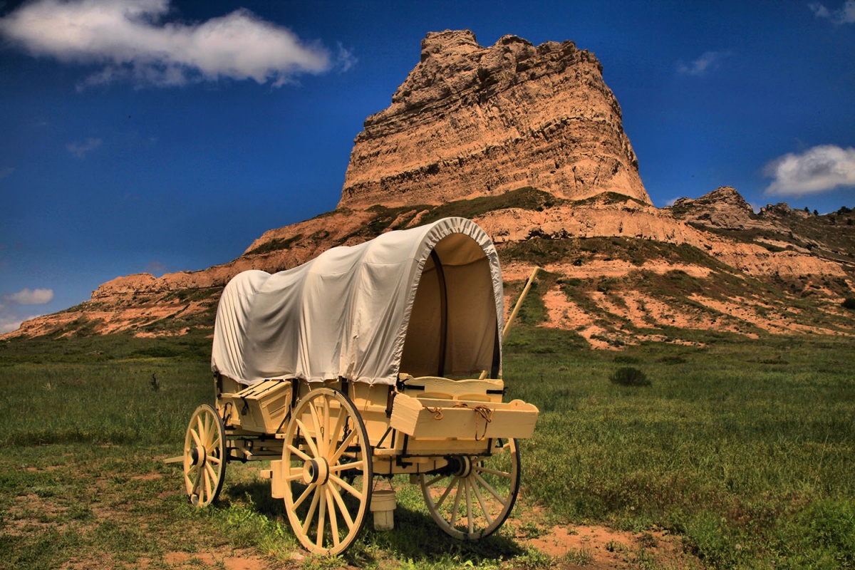 A covered wagon sits in front of land formation
