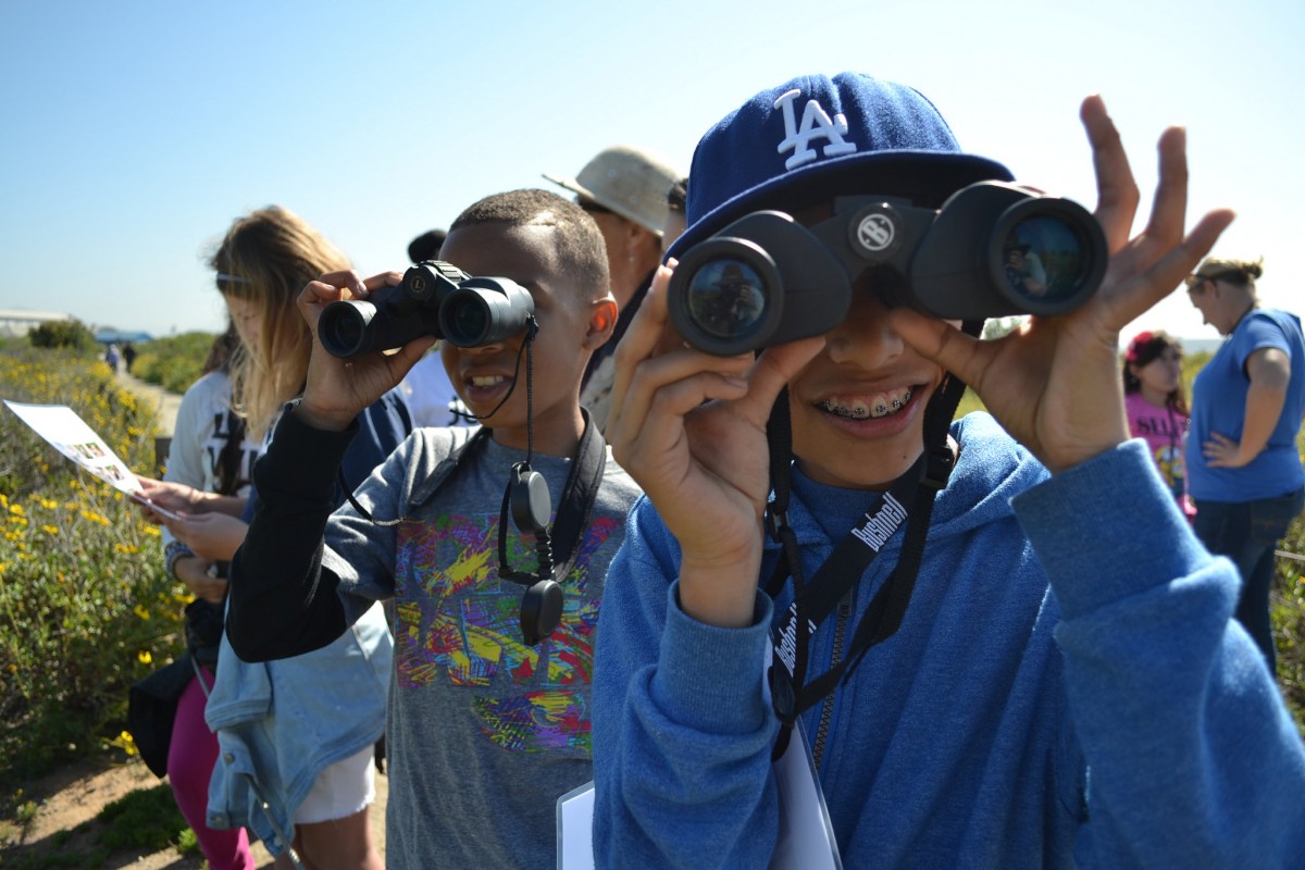 Teenagers look through binoculars at the camera