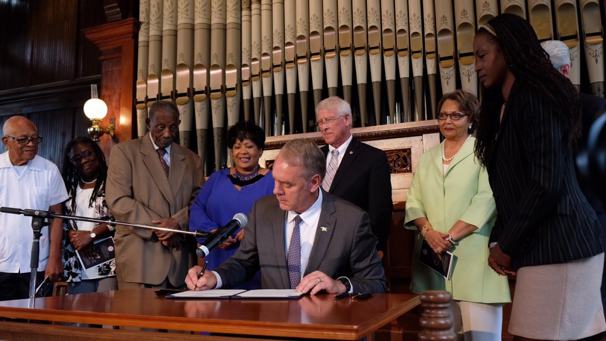 Secretary Zinke signs a designation with a group behind him