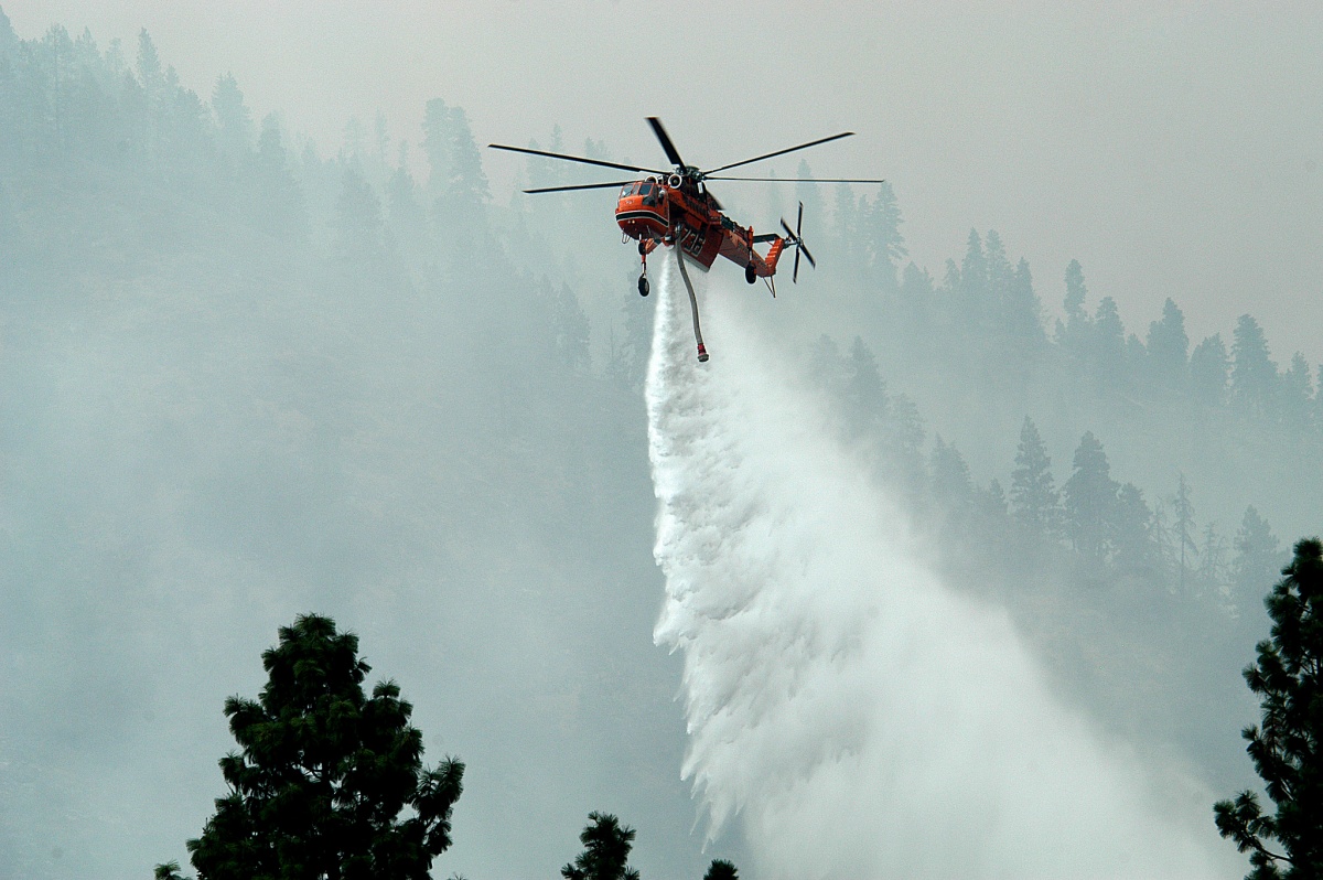A helicopter drops water on a wildfire